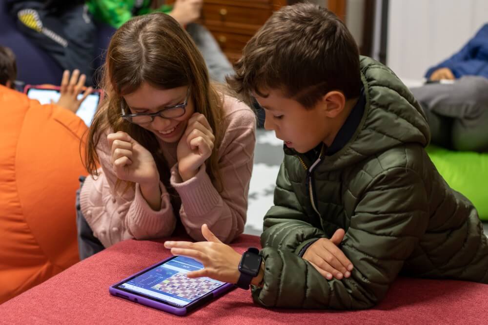 kid teach to his peer how to use HOC Academy app